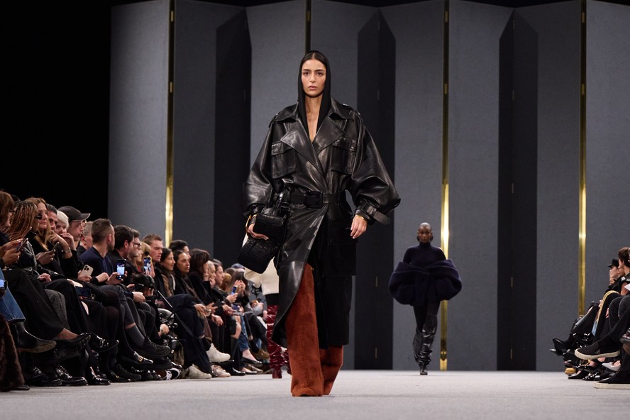 Aqui, um look que mistura trench coat utilitário com a silhuetas ampla acinturada e ombros largos marcados