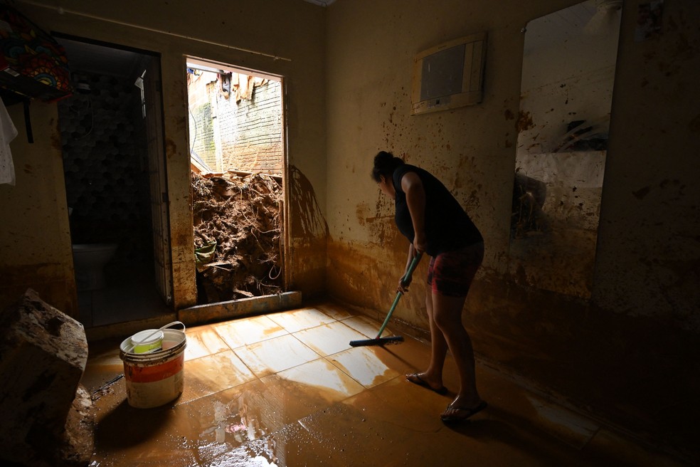 Mulher remove lama de sua casa, que foi inundada após fortes chuvas e deslizamentos no distrito de Juquehy, em São Sebastião, São Paulo - 20 de fevereiro de 2023 — Foto: Nelson Almeida/AFP/Getty Images